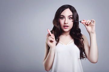 Beautiful woman with mascara on grey background