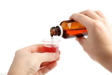 Female hands pouring medical syrup in measuring plastic cup on white background - obrazy, fototapety, plakaty