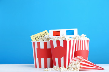 Popcorn in striped buckets with glasses on blue background