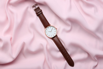 Wrist watch on pink satin background