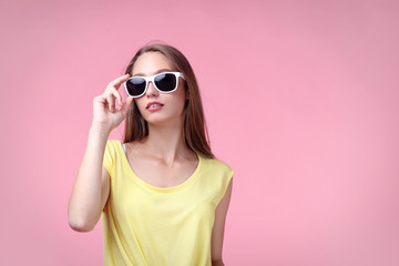 Portrait of young woman in sunglasses on pink background