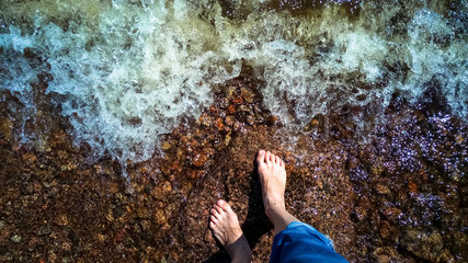 Feet in the dark water of an approaching wave.