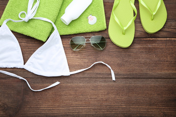 Swimsuit with flip flops and towel on wooden table
