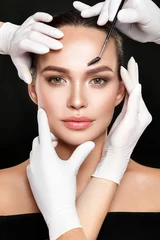 Schönes Frauenporträt mit klassischem Make-up und Händen in medizinischen Handschuhen mit kosmetischem Werkzeug. © demidenko