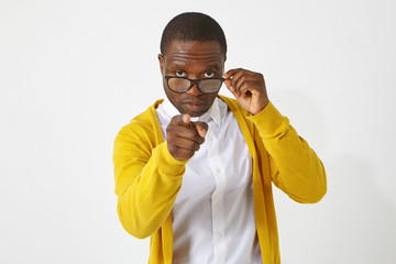 Serious confident dark skinned male teacher in eyewear pointing index finger at camera, having...