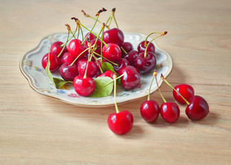 Naklejka na ściany i meble Plate of cherries on a wooden background.
