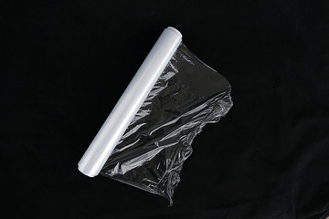 wrapping plastic transparent food film on black background.  food packaging stretch film     © kodbanker