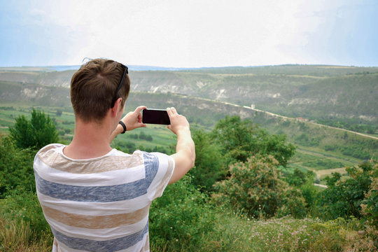 Young man making mobile photo of landscape