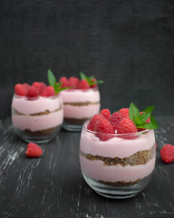 Sweet raspberry mousse in glass bowl on dark background