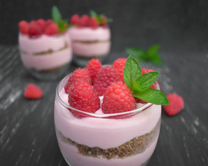 Sweet raspberry mousse in glass bowl on dark background