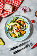 Salad with tomatoes and avocado on concrete background.