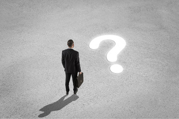 Confused businessman looking at question mark on the floor