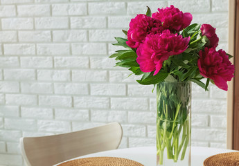 Pink peonies in a glass vase standing on the table.