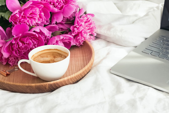 Coffe, peonies and laptop on the bed