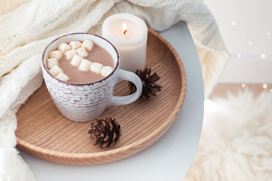 Hot cocoa with marshmallows, knitted sweater and burning candle