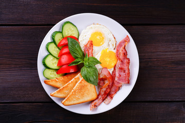 Continental breakfast. Fried eggs with bacon, toasts and fresh vegetables. Morning meals, tasty and nourishing day starter