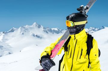 A portrait of a skier in a protective helmet and glasses is a mask and scarf with skis on his...