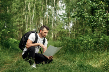 Fototapeta premium Portrait of a young man, a wanderer with a backpack. Goes on the road with a copy space, a happy tourist on a summer day, a traveler enjoying his time relaxing in nature.