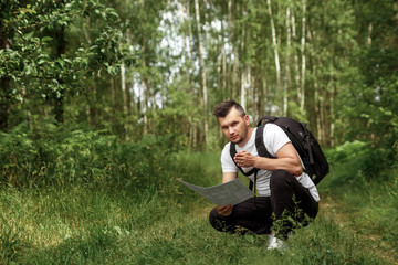 Portrait of a young man, a wanderer with a backpack. Goes on the road with a copy space, a happy tourist on a summer day, a traveler enjoying his time relaxing in nature.