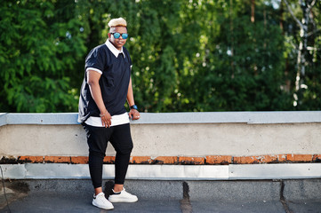 Obraz premium Stylish arabian muslim boy with originally hair and sunglasses posed on streets at roof.