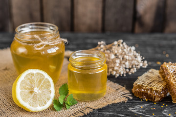 Beautiful transparent honey in bank, honeycombs and pollen on a wooden table. It can be used as a background