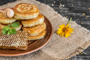 Beautiful transparent honey in bank, honeycombs and pollen on a wooden table. It can be used as a background