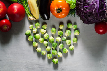 briussel cabbage in the shape of heart and fresh vegetables for healthy cooking on a light wooden background, flat lay, copy space, close-up. Diet, pure food or the concept of vegetarian food.