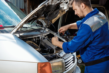 Male hands close-up with wrenches. The auto mechanic works in the garage. Repair service. Maintenance of the car, car repair.