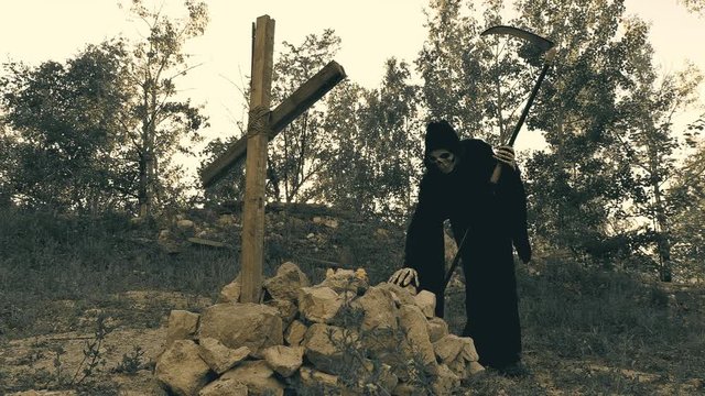 death with a scythe lies on the grave of the one whom she took with her