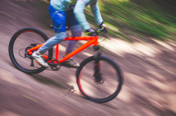 Naklejka premium Rowerzysta schodzi z góry na pomarańczowym rowerze, rozmycie ruchu