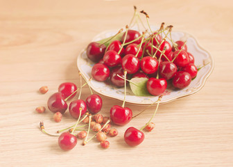 Plate of cherries on a wooden background, toned.