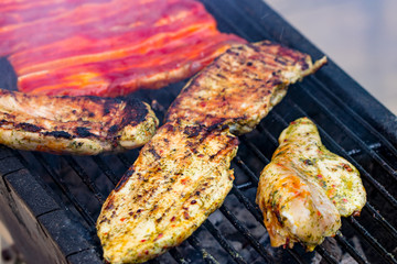 Assorted mixed grill from chicken meat, and pork, sausages  roasting on barbecue grid cooked for summer family dinner