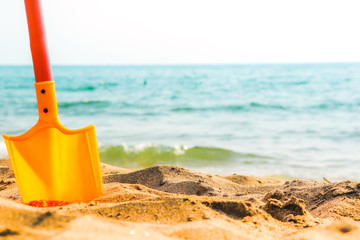 Fototapeta na wymiar Summer beach sea horizon with toy shovel standing in sand. Copyspace