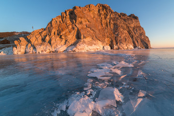 Lake Baikal in winter day. Cracks on the smooth surface of the ice near the cliffs of Olkhon Island