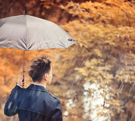 Autumn rainy weather and a young man with an umbrella