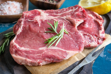 Cutting beef for grilling on a wooden cutting Board with Bay leaf, rosemary for marinade in a rustic style. Close-up.