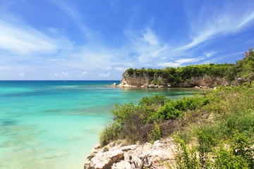 Seascape view rocky shoreline with azure calm ocean and bright blue sky location at Macao beach in tropical island Dominican republic.