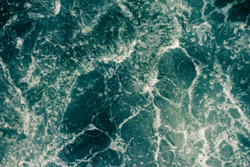 The surface of the sea with waves, foam and bubbles, green abstract background