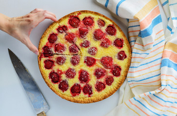 Homemade strawberry pie with coconut chips. The hand takes a slice of pie.