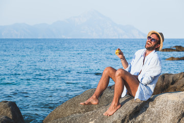 Young man eating corn on the beach © marjan4782