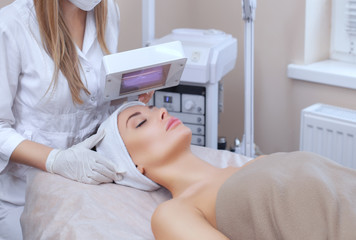 The cosmetologist uses the Wood Lamp for detailed diagnosis of the skin condition. The device detects the presence of skin diseases or inflamed areas. Cosmetology and professional care.