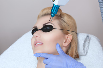 Laser tattoo removal on woman's eyebrows in a beauty salon