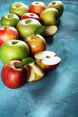 Ripe red apples with leaves on wooden background.