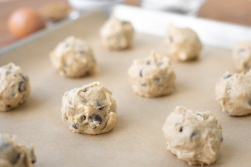 Close up on chocolate chip cookie dough balls on parchment paper
