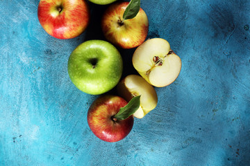 Ripe red apples with leaves on wooden background.
