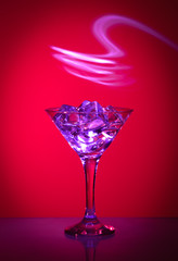  a martini glass with ice cubes on a red background
