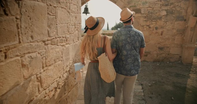 Young tourists couple visiting old stone church on Mediterranean island