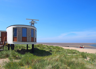 the old coastguard station in fleetwood with radar antennae with crass covered dunes leading to the beach on a summers day in bright sunlight with blue sky