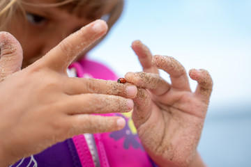 Girl on the beach examining ladybug