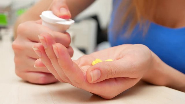 Woman pouring bunch of prescription yellow opiate pills into hand